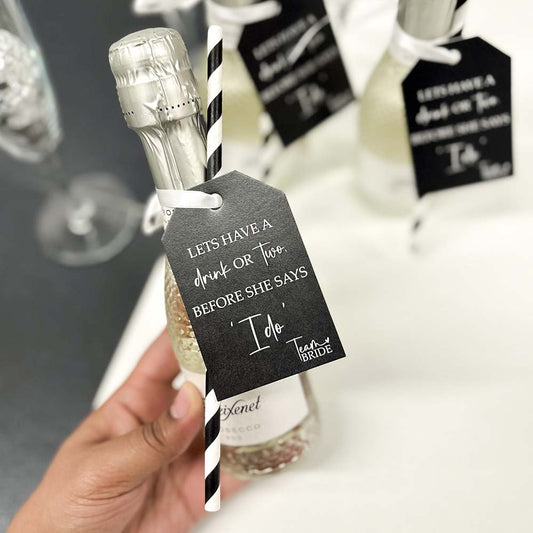Black and white Team Bride Hen Party Bottle Tag attached to a mini bottle of prosecco.