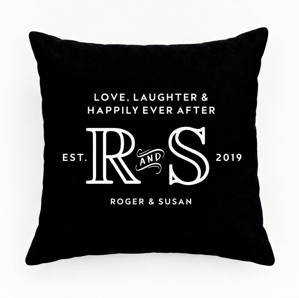 A square black cushion with white printed text and monogram design reading 'LOVE, LAUGHTER & HAPPILY EVER AFTER', large 'R & S' initials, 'EST. 2019', and 'ROGER & SUSAN'.