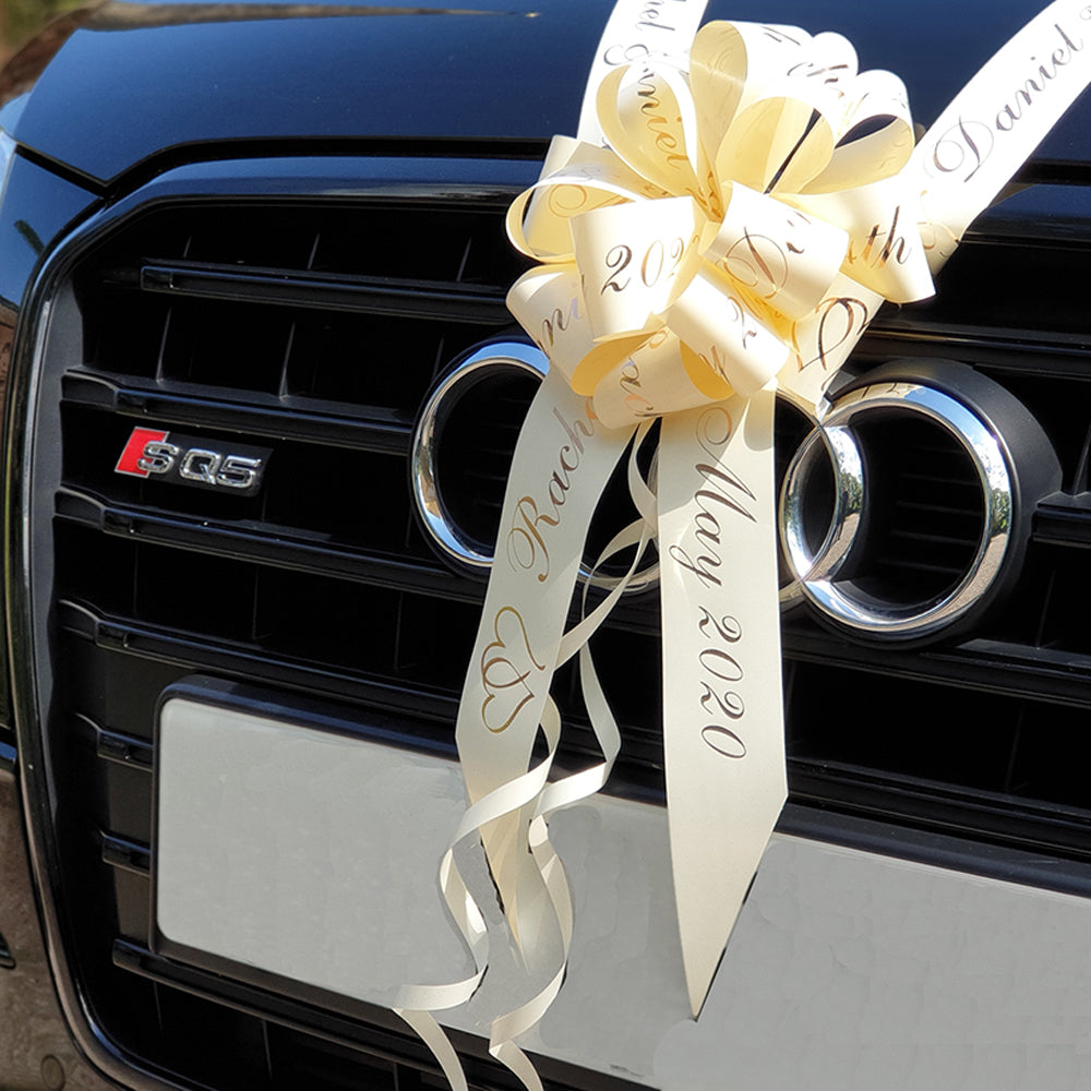 A black car with an ivory and rose gold personalised wedding car kit. 