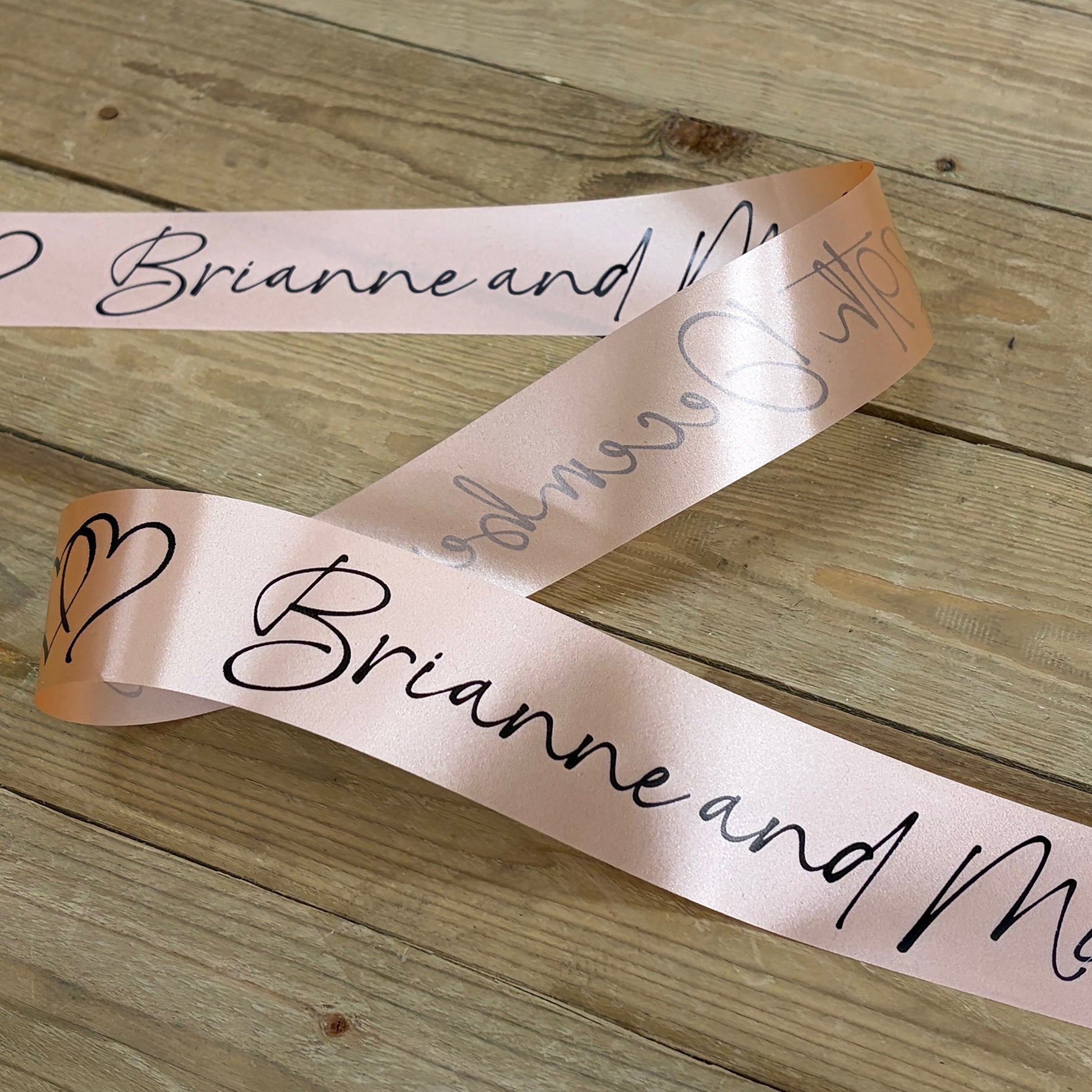 Personalised wedding car ribbon in peach with black print.