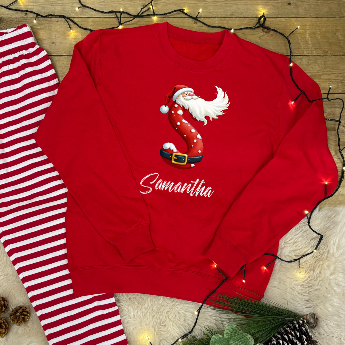A Red Sweatshirt with a Santa Initial Design and name underneath with matching red and white striped lounge pants.