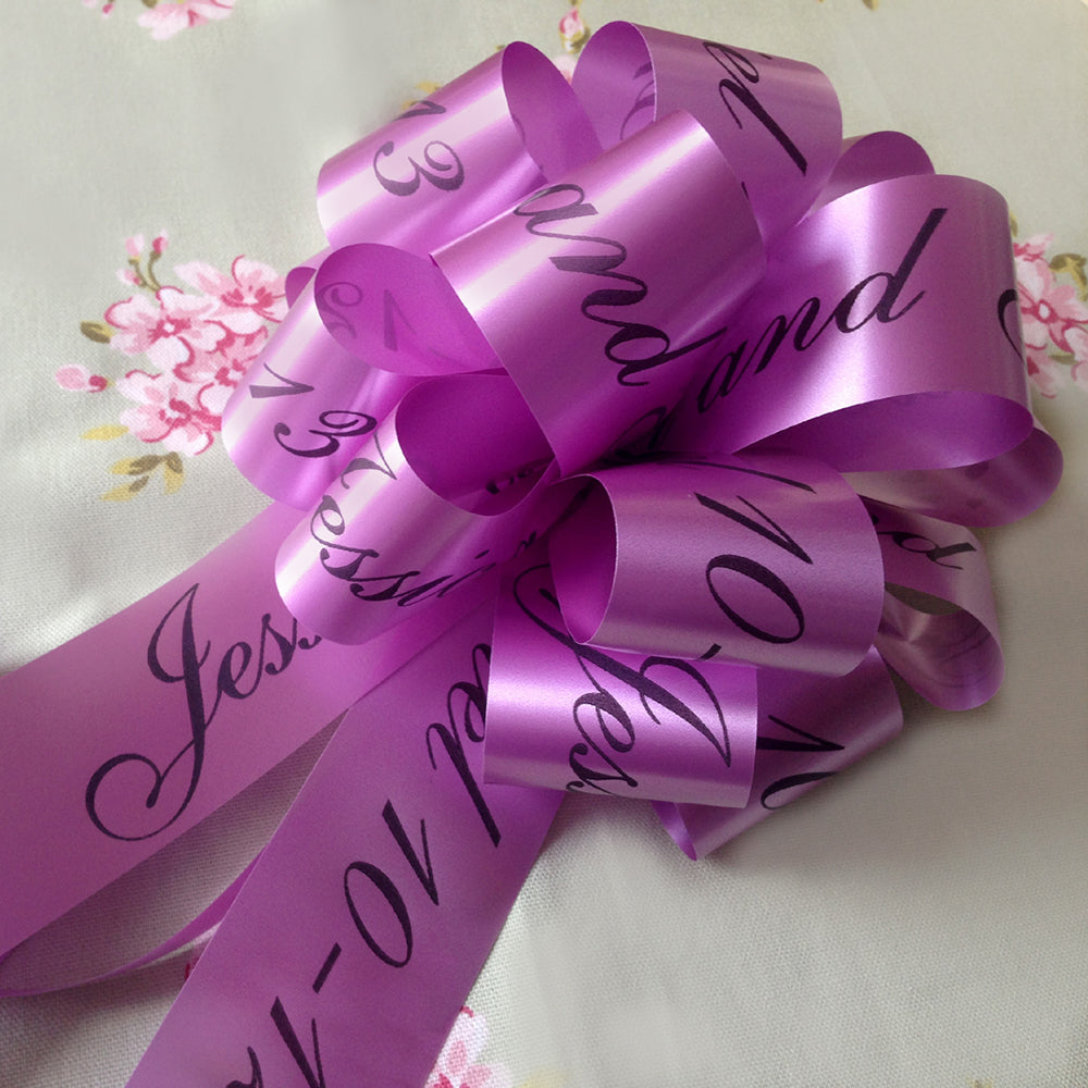 A personalised wedding car bow in orchid with black print. 