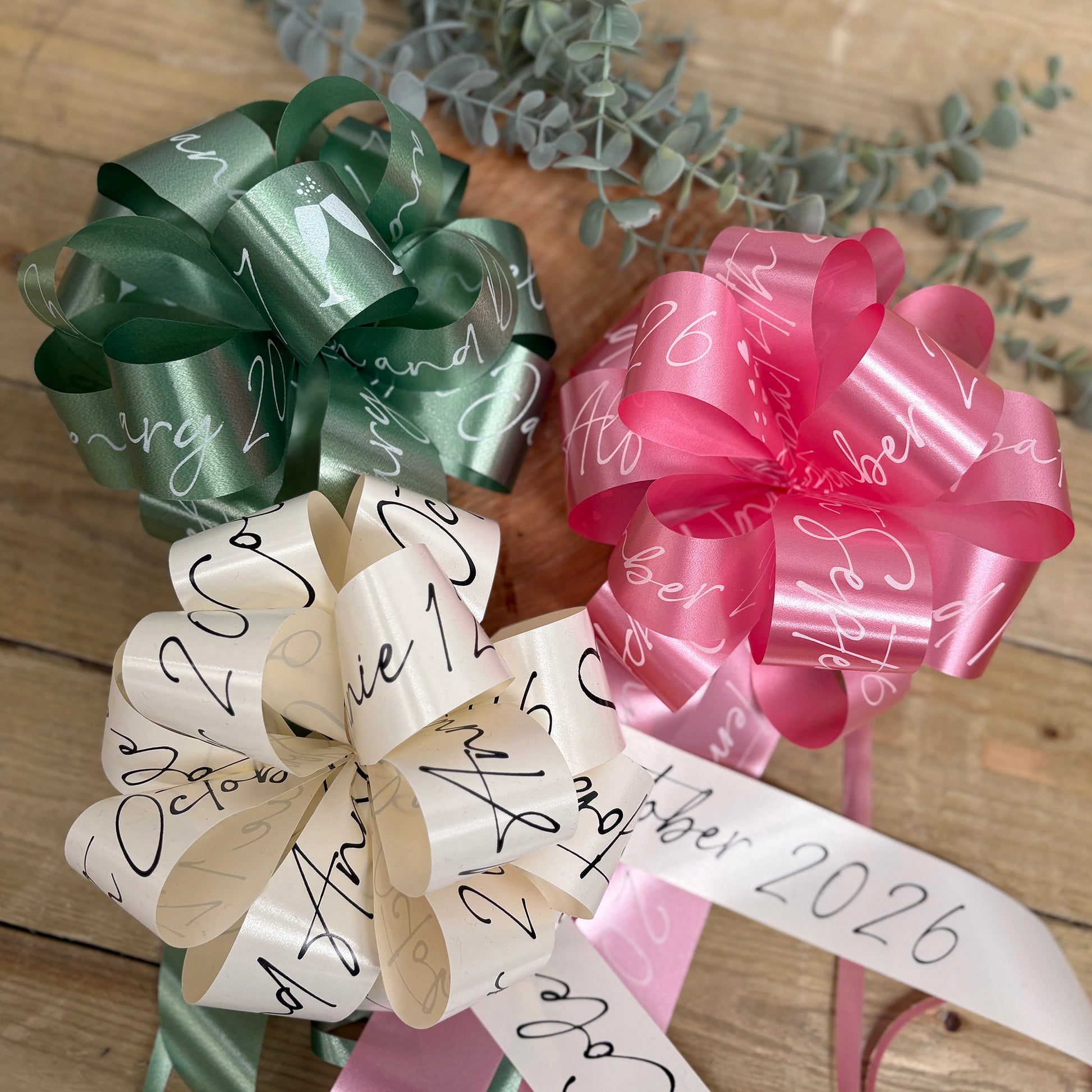 A group of personalised wedding car bows in sage green, ivory and rose pink. 