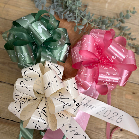 A group of personalised wedding car bows in sage green, ivory and rose pink. 